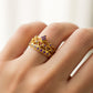 Mano de mujer usando un anillo con forma de corona en el centro en oro amarillo de 18 quilates con cristales de color morado de Joyería Caracas. 
