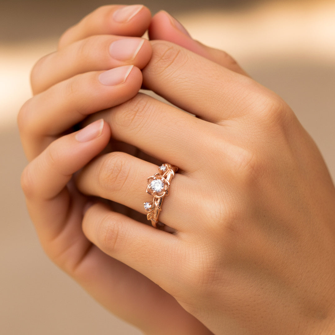 Mano de mujer usando un anillo con forma de rosas y espinas en oro rosa de 18 quilates con cristales de color blanco de Joyería Caracas. 