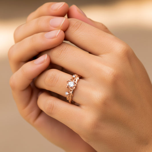 Mano de mujer usando un anillo con forma de rosas y espinas en oro rosa de 18 quilates con cristales de color blanco de Joyería Caracas. 