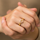 Mano de mujer usando un anillo con forma de corazón en el centro con el número 15 en el centro en oro amarillo de 18 quilates con cristales de color rosado de Joyería Caracas. 