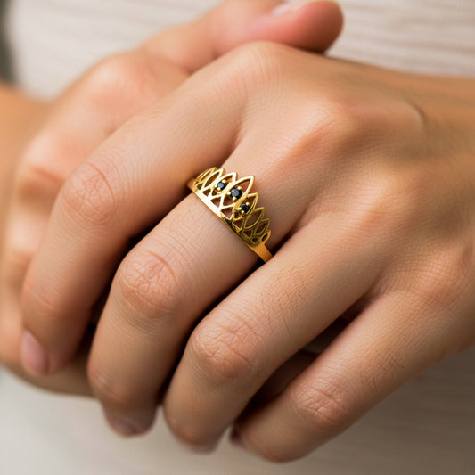 Mano de mujer usando un anillo con forma de corona en oro amarillo de 18 quilates con 3 Diamantes de color negro de Joyería Caracas.