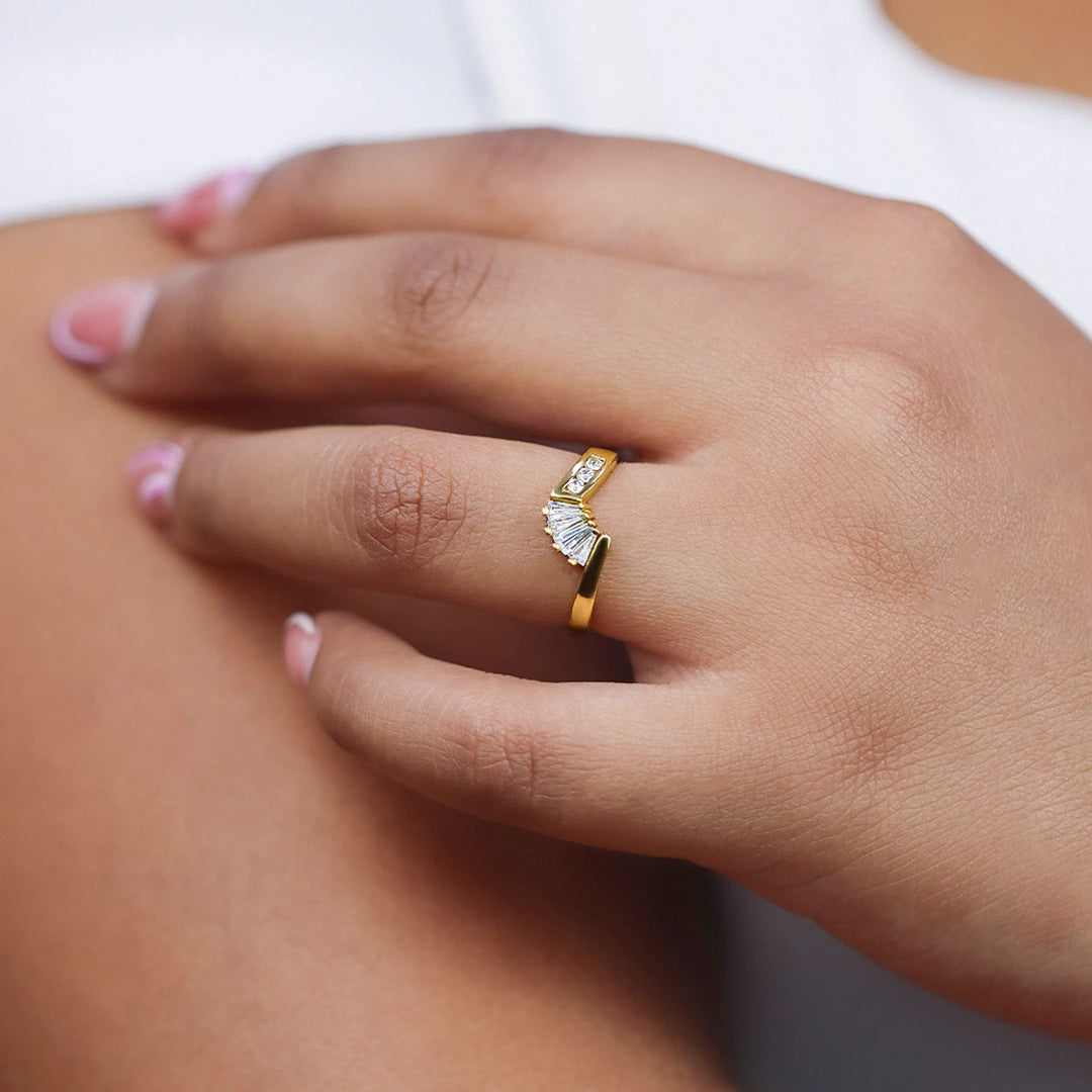 Mano de mujer con anillo pisargolla en oro amarillo de 18 quilates con cristal en un lateral de color blanco y cristales en forma de trapecios de color blanco de Joyería Caracas.