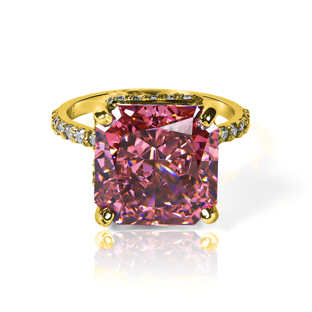 Anillo Zafiro Padparadscha sintético, este anillo presenta un zafiro sintético, reconocido por su tonalidad única que combina matices rosados y anaranjados, acompañado de moissanitas que realzan su brillo. Elaborado en oro de 18k.