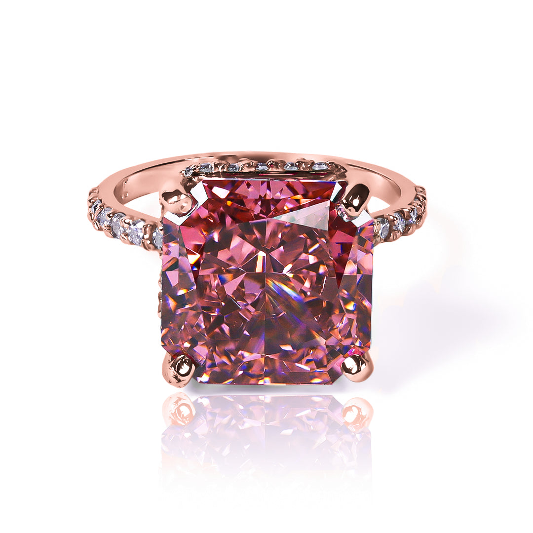 Anillo Zafiro Padparadscha sintético, este anillo presenta un zafiro sintético, reconocido por su tonalidad única que combina matices rosados y anaranjados, acompañado de moissanitas que realzan su brillo. Elaborado en oro de 18k.