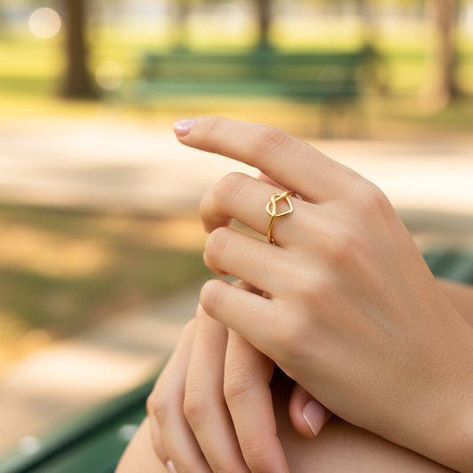 Mano de modelo usando un anillo minimalista con forma de corazón en oro amarillo de 18 quilates de Joyería Caracas. 