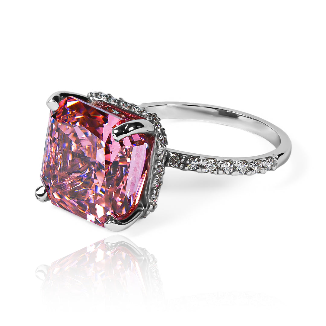 Anillo Zafiro Padparadscha sintético, este anillo presenta un zafiro sintético, reconocido por su tonalidad única que combina matices rosados y anaranjados, acompañado de moissanitas que realzan su brillo. Elaborado en oro de 18k.