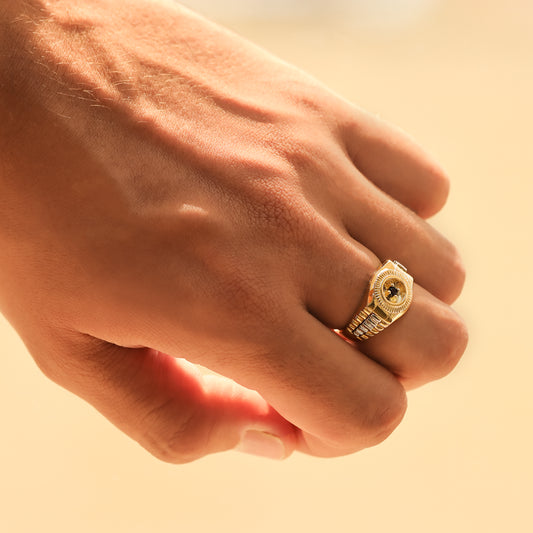 Mano de hombre con anillo clásico inspirado en un reloj en oro amarillo y blanco de 18 quilates, fabricado en Joyería Caracas.
