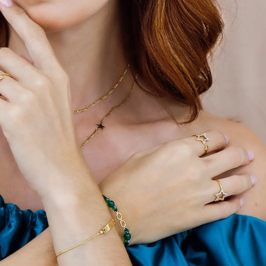 Mano de mujer usando un anillo con forma de 2 estrellas en cada punta en oro amarillo de 18 quilates con cristales de color blanco en una de ellas, fabricado en Joyería Caracas. 