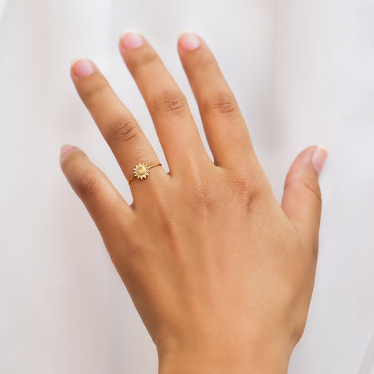 Mano de mujer con anillo con forma de girasol en el centro en oro amarillo de 18 quilates, fabricado en Joyería Caracas. 