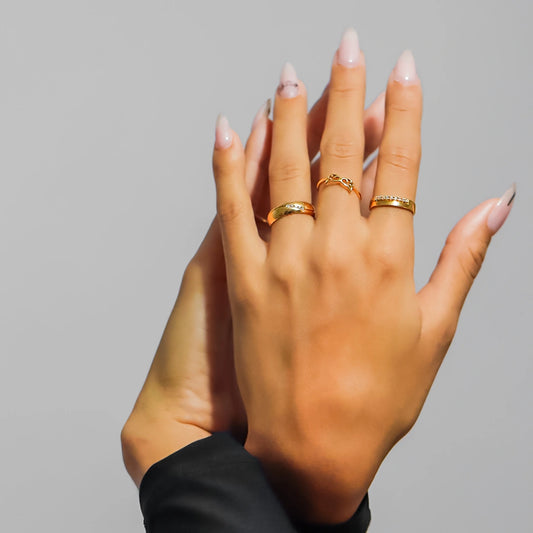 Mano de mujer usando un anillo en oro amarillo de 8 quilates con cristales de color blanco en el orillo de Joyería Caracas. 