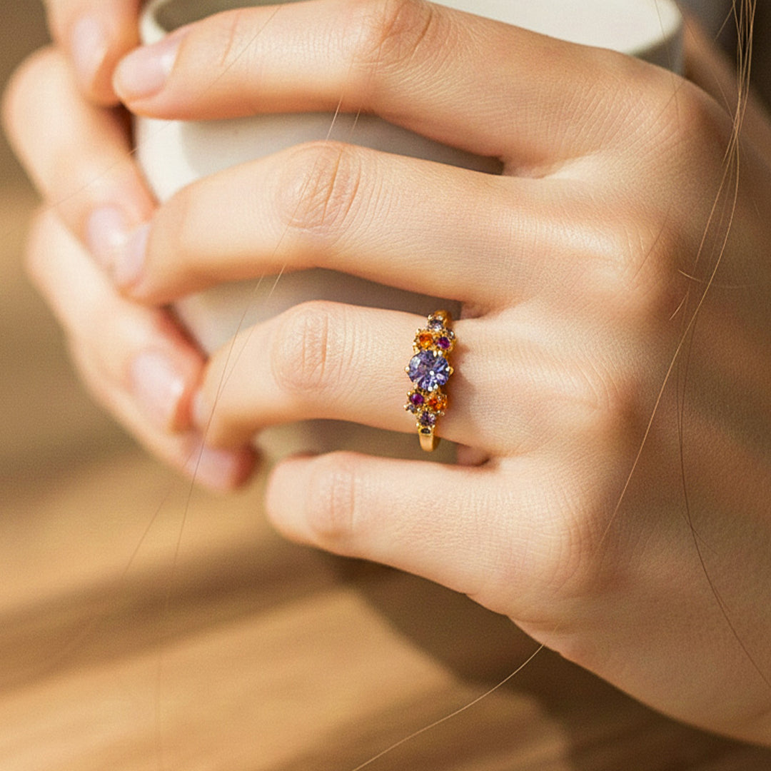 Mano de modelo usando un anillo en oro amarillo de 18 quilates con cristales de distintos colores de Joyería Caracas. 