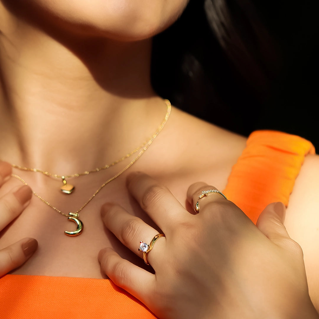 Mano de mujer usando un anillo en oro amarillo de 18 quilates con cristal en el centro de color blanco de Joyería Caracas.