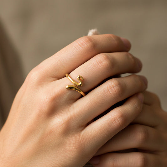 Mano de mujer con anillo en forma de serpiente lisa en oro amarillo de 18 quilates de Joyería Caracas. 