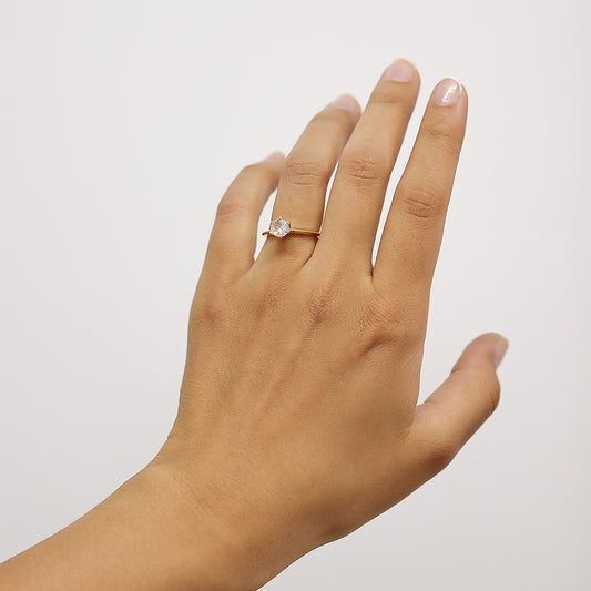Mano de mujer usando un anillo de compromiso en oro amarillo de 18 quilates con cristal de color blanco en el centro de Joyería Caracas. 