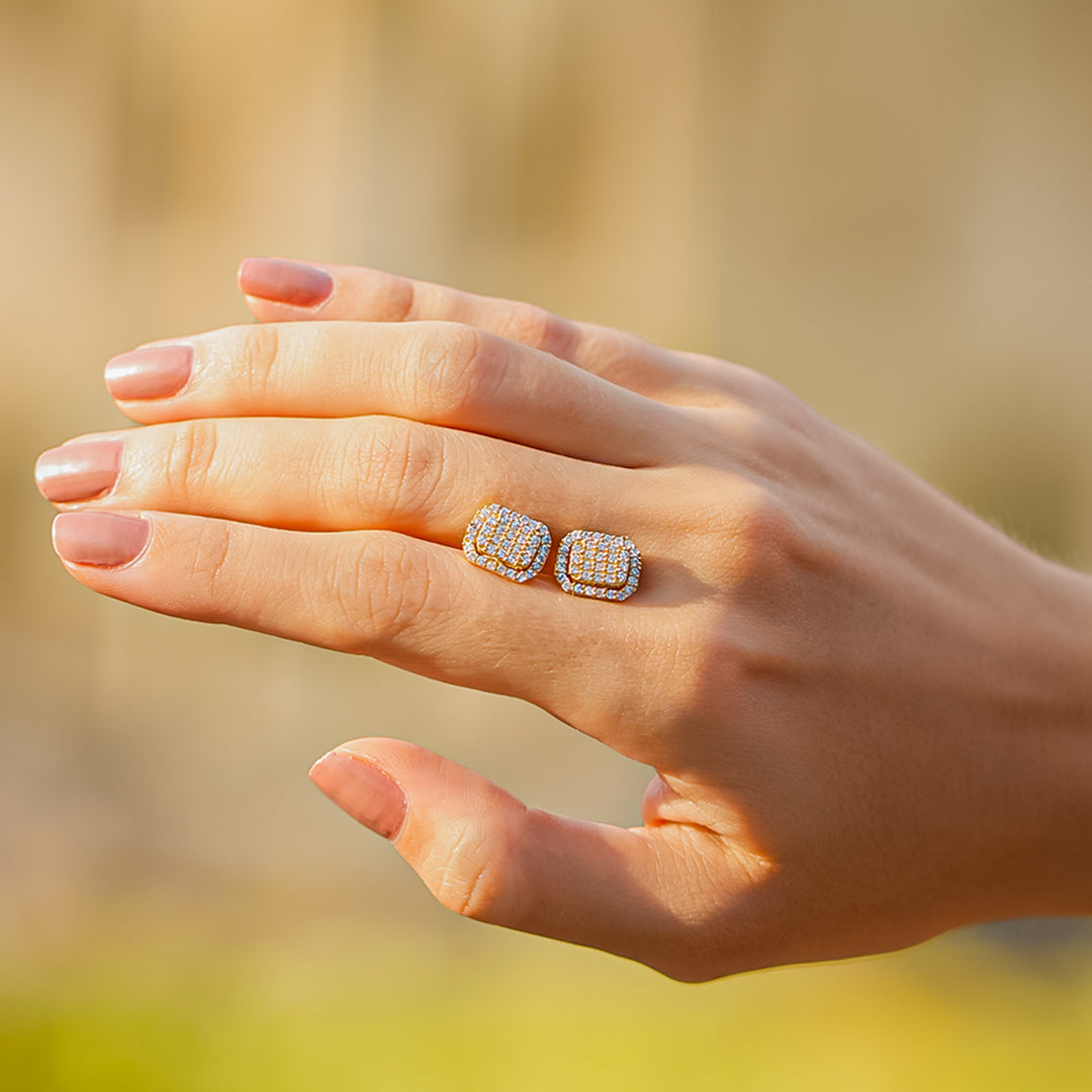 Mano de mujer con topitos en forma rectangular en oro amarillo de 18 quilates, con cristales de color blanco, hecho en Joyería Caracas.  