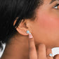 Oreja de mujer con aretes en forma de flor en oro blanco de 18 quilates con Diamante central de color celeste y Diamantes de color blanco alrededor, fabricado en Joyería Caracas.