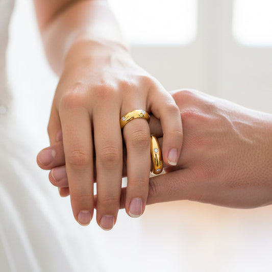 Manos de una pareja usando unas argollas de matrimonio en oro amarillo de 18 quilates con cristales de Joyería Caracas. 