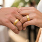 Manos de una pareja usando unas argollas en oro amarillo de 18 quilates de Joyería Caracas. 