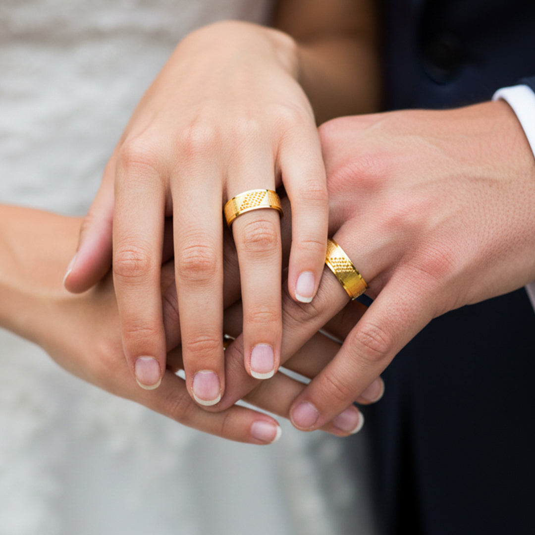 Manos de una pareja usando unas argollas en oro amarillo de 18 quilates de Joyería Caracas. 