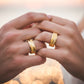 Manos de una pareja usando unas argollas en oro amarillo de 18 quilates de Joyería Caracas.