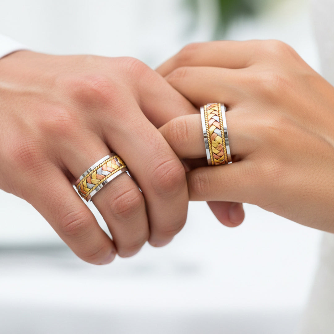 Manos de una pareja usando unas argollas trenzadas en oro amarillo, blanco y rosa de 18 quilates de Joyería Caracas.