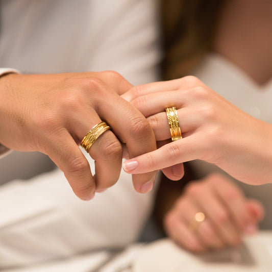 Manos de una pareja usando unas argollas en oro amarillo de 18 quilates de Joyería Caracas.