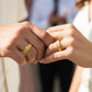 Manos de una pareja usando unas argollas en oro amarillo de 18 quilates de Joyería Caracas. 