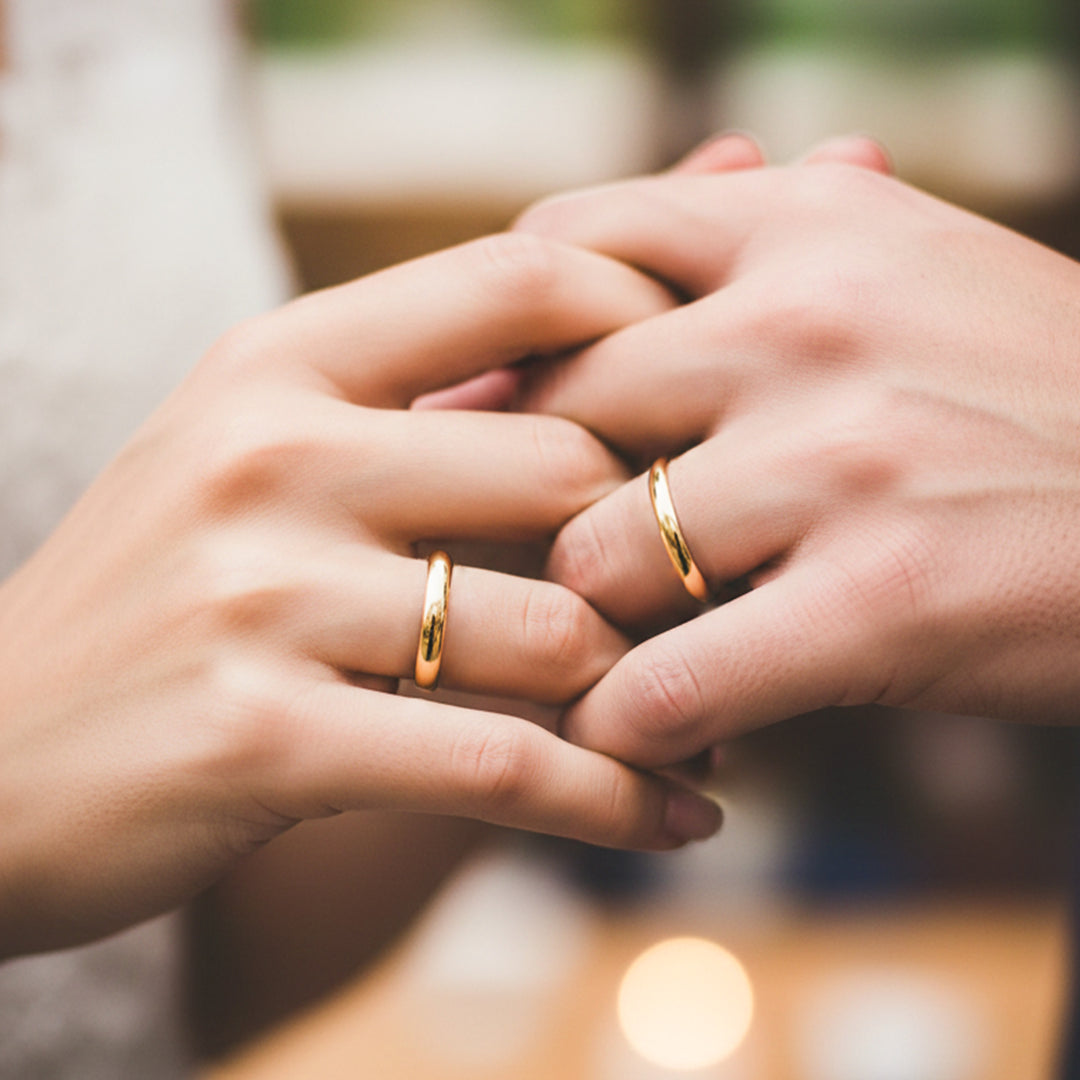 Manos de una pareja usando unas argollas en oro amarillo de 18 quilates de Joyería Caracas.