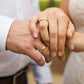 Manos de una pareja usando unas argollas de matrimonio en oro amarillo cóncavas clásicas de 18 quilates de Joyería Caracas.