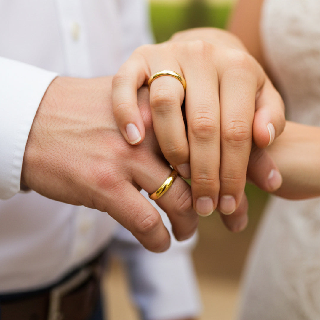 Manos de una pareja usando unas argollas de matrimonio en oro amarillo cóncavas clásicas de 18 quilates de Joyería Caracas.