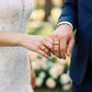 Manos de una pareja usando unas argollas de matrimonio en oro amarillo de 18 quilates con cristales verdes de Joyería Caracas. 
