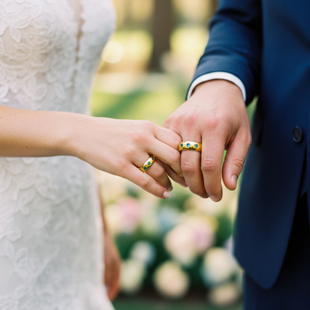 Manos de una pareja usando unas argollas de matrimonio en oro amarillo de 18 quilates con cristales verdes de Joyería Caracas. 