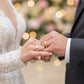 Manos de una pareja usando unas argollas de matrimonio en oro amarillo de 18 quilates con cristales de Joyería Caracas. 