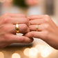 Manos de una pareja usando unas argollas en oro amarillo de 18 quilates de Joyería Caracas.