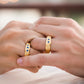 Manos de una pareja usando unas argollas en oro amarillo de 18 quilates facetadas con cristales azules de Joyería Caracas.