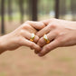 Manos de una pareja usando unas argollas de matrimonio en oro amarillo de 18 quilates con 3 cristales de Joyería Caracas. 