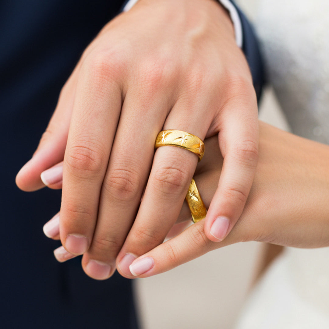 Manos de una pareja usando unas argollas en oro amarillo de 18 quilates de Joyería Caracas. 