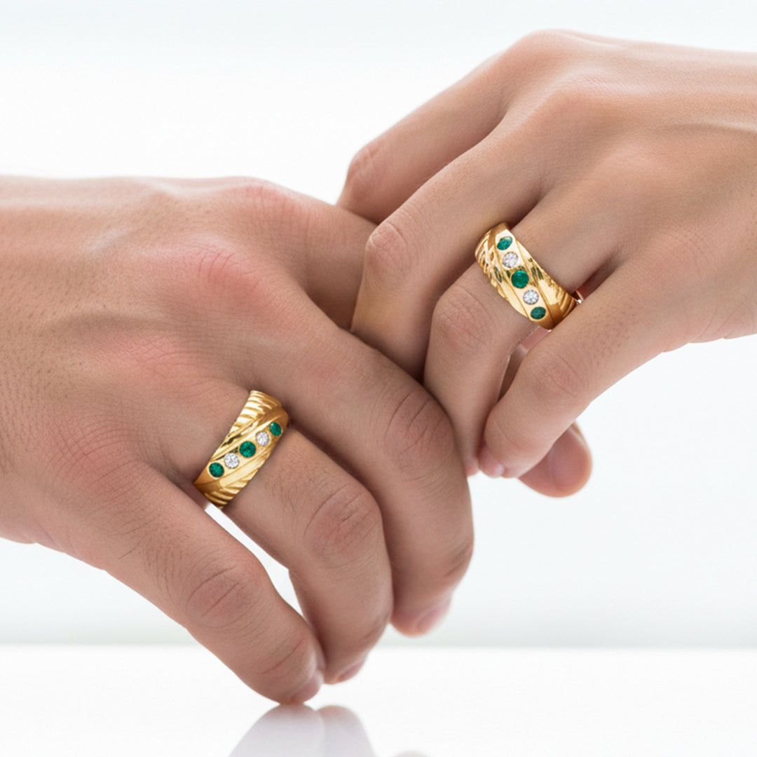 Manos de una pareja usando unas argollas en oro amarillo con cristales verdes y blancos de 18 quilates de Joyería Caracas.