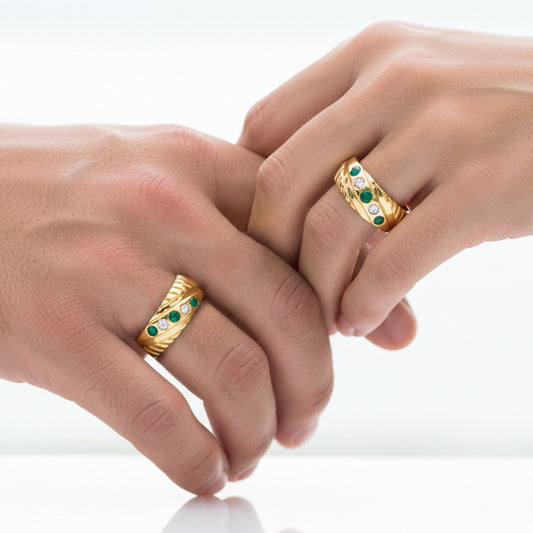 Manos de una pareja usando unas argollas en oro amarillo con cristales verdes y blancos de 18 quilates de Joyería Caracas.