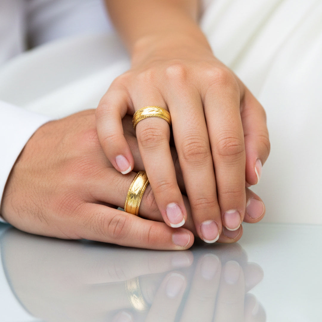 Manos de una pareja usando unas argollas en oro amarillo de 18 quilates de Joyería Caracas. 