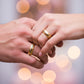 Manos de una pareja usando unas argollas en oro amarillo y blanco de 18 quilates de Joyería Caracas.