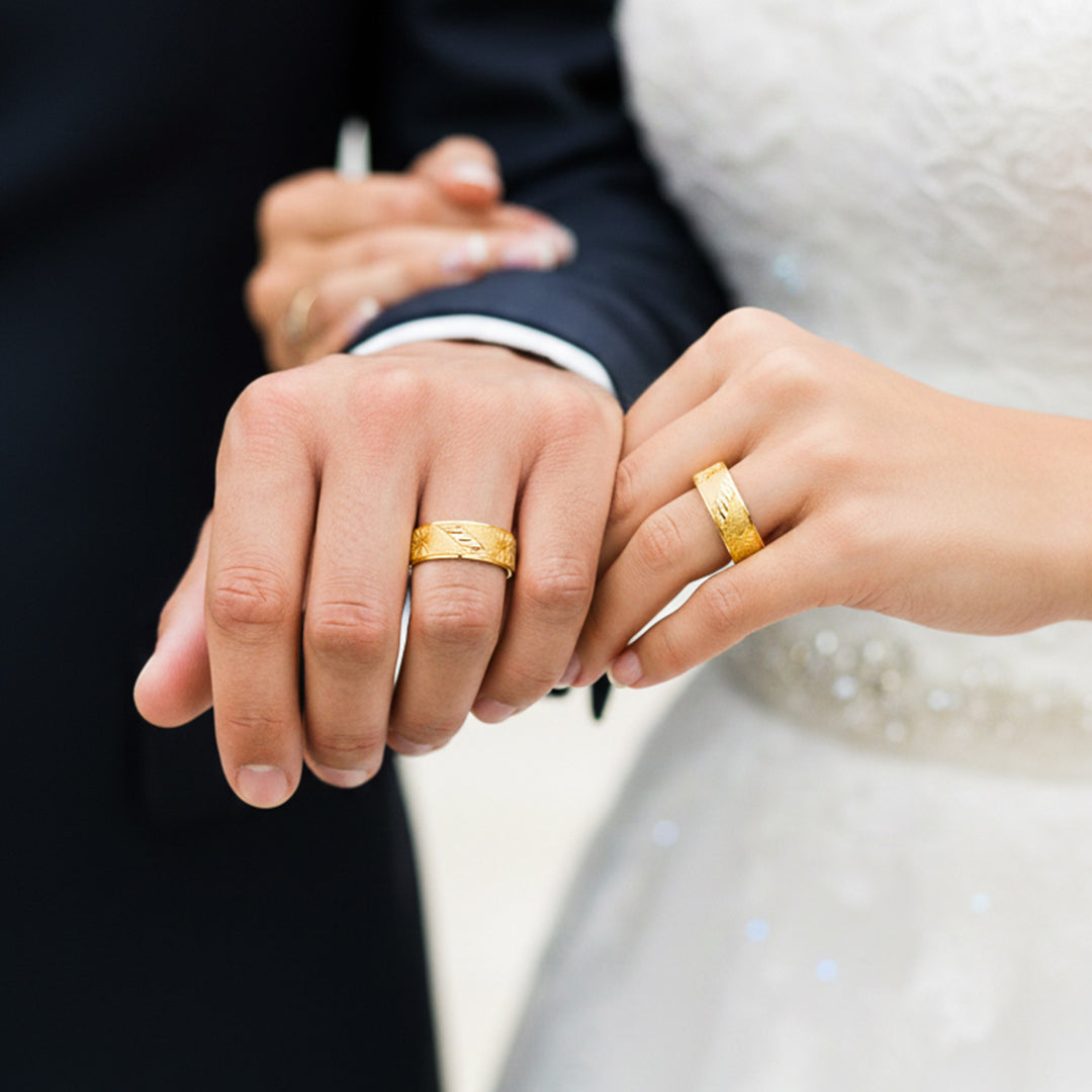 Manos de una pareja usando unas argollas en oro amarillo de 18 quilates de Joyería Caracas. 
