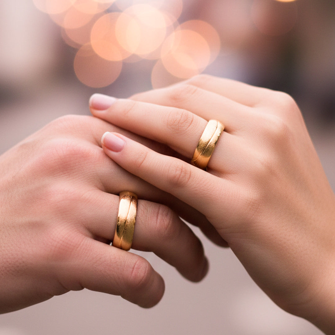 Manos de una pareja usando unas argollas en oro amarillo de 18 quilates de Joyería Caracas.
