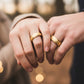 Manos de una pareja usando unas argollas en oro amarillo de 18 quilates de Joyería Caracas.