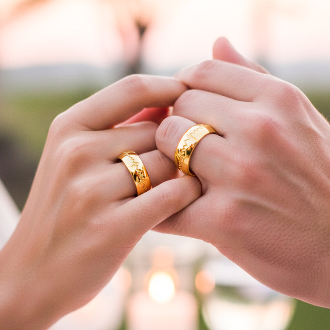Manos de una pareja usando unas argollas en oro amarillo de 18 quilates de Joyería Caracas.