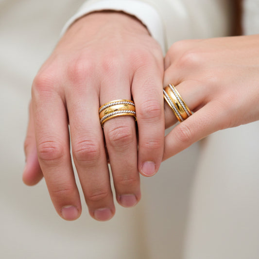 Manos de una pareja usando unas argollas de matrimonio en oro amarillo y blanco de 18 quilates de Joyería Caracas. 