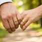 Manos de una pareja usando unas argollas de matrimonio en oro amarillo de 18 quilates de Joyería Caracas. 