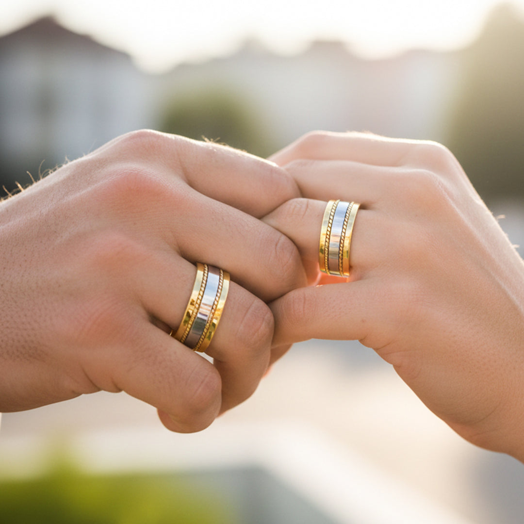 Manos de una pareja usando unas argollas de matrimonio en oro amarillo y blancos planas de 18 quilates de Joyería Caracas. 