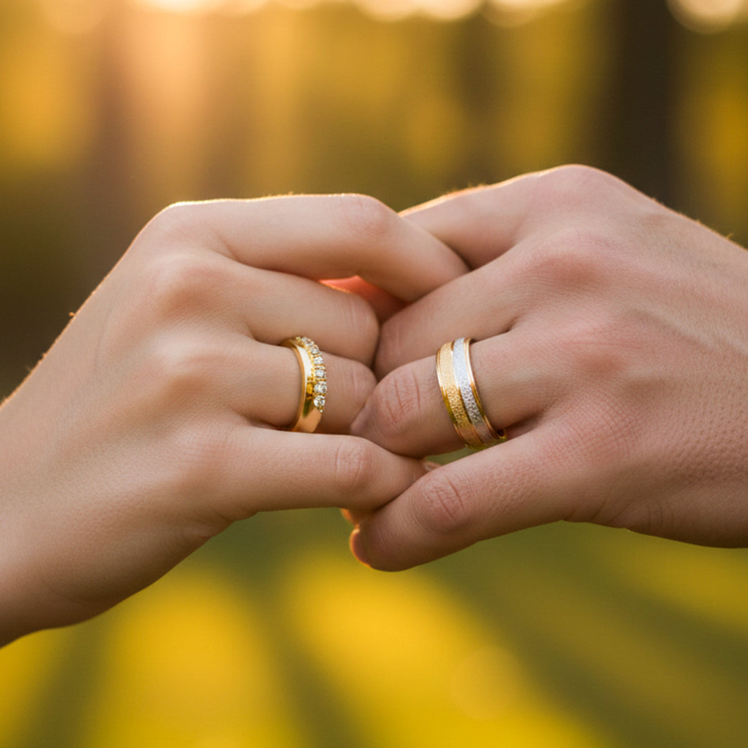 Manos de una pareja usando unas argollas de matrimonio lisas y facetadas en oro amarillo y blanco de 18 quilates con cristales de Joyería Caracas. 