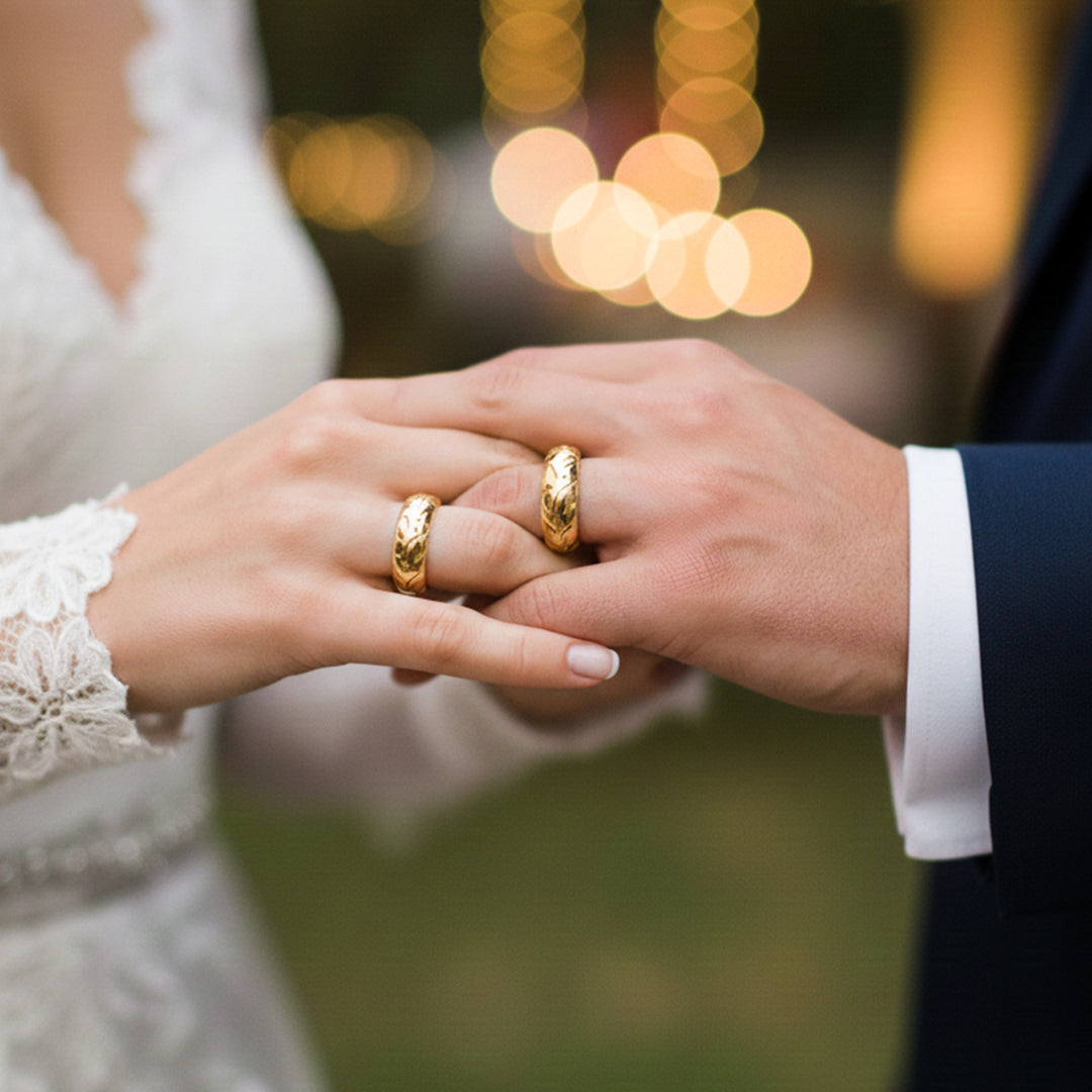 Manos de una pareja usando unas argollas de matrimonio en oro amarillo de 18 quilates de Joyería Caracas. 